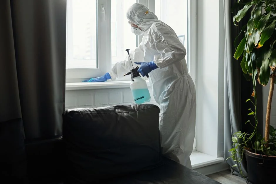Anonymous person in yellow rubber gloves using simple sponge for cleaning mirror in bathroom